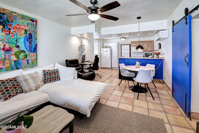 living room with light tile patterned floors, a wall unit AC, a barn door, ceiling fan, and a textured ceiling