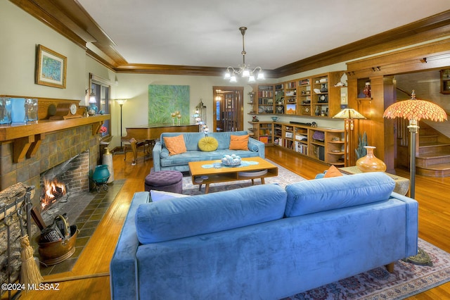 living room with hardwood / wood-style floors, a fireplace, an inviting chandelier, and ornamental molding