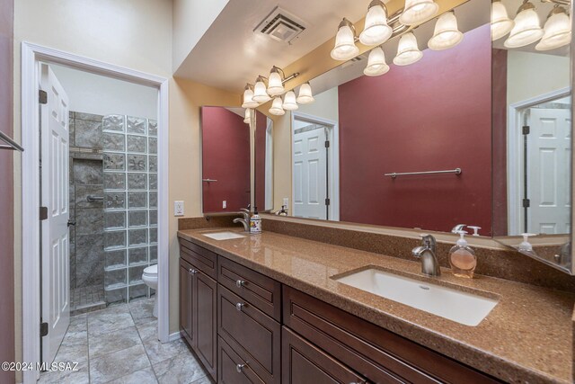 bathroom with vanity, toilet, and tiled shower