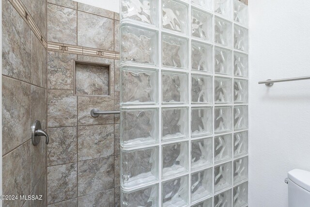 bathroom with tiled shower and toilet