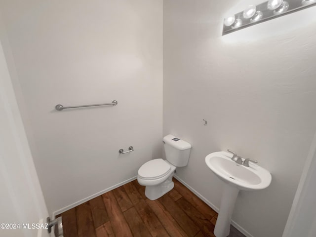 bathroom with baseboards, toilet, and wood finished floors