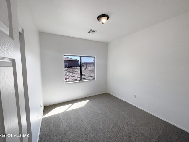 unfurnished room featuring baseboards, visible vents, and dark carpet