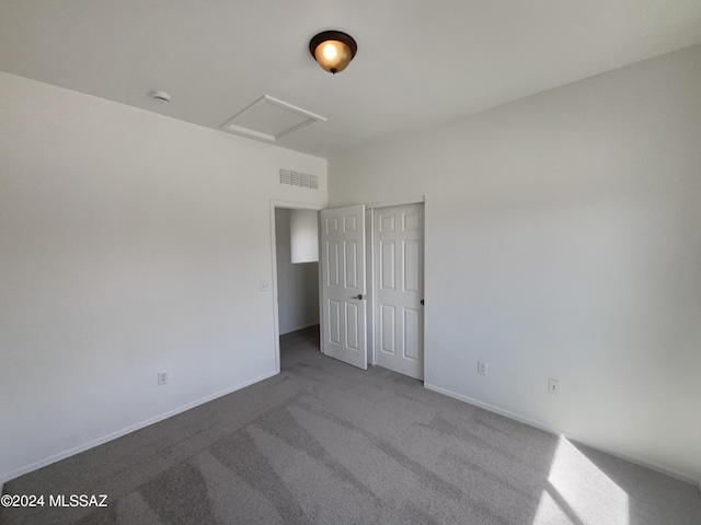 carpeted empty room with attic access, baseboards, and visible vents