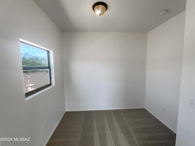 spare room with dark carpet and baseboards