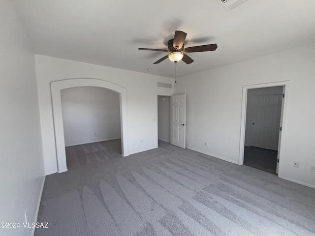 unfurnished bedroom with arched walkways, visible vents, and carpet floors