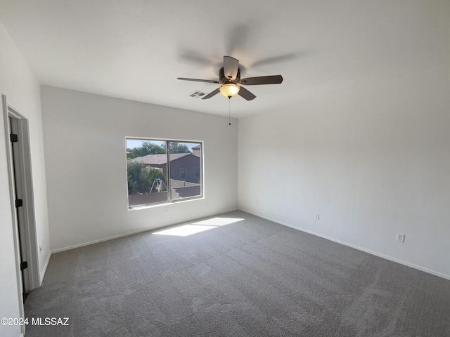 carpeted spare room with visible vents, baseboards, and ceiling fan