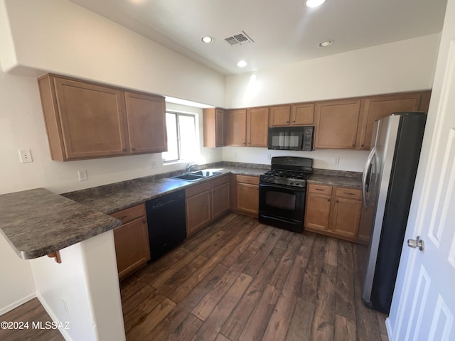 kitchen featuring dark wood-style floors, visible vents, a peninsula, black appliances, and dark countertops