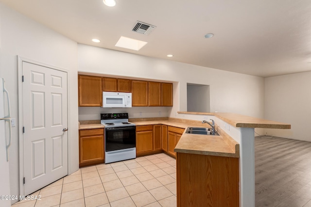 kitchen with light wood-type flooring, white appliances, kitchen peninsula, sink, and a breakfast bar area