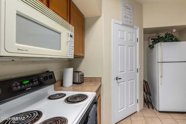 kitchen with white appliances and light tile patterned flooring