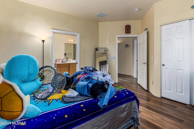 bedroom with ensuite bath and dark hardwood / wood-style floors