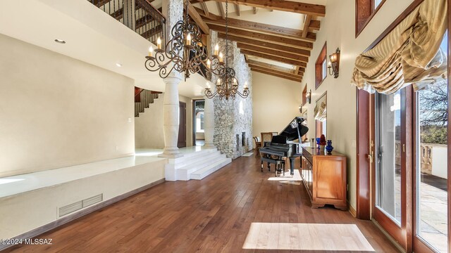 interior space with decorative columns, a notable chandelier, dark hardwood / wood-style flooring, and a high ceiling