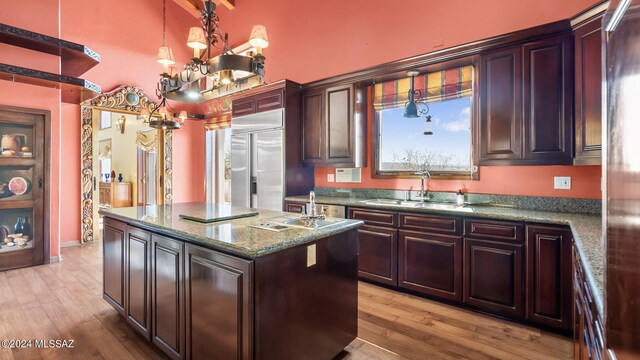 kitchen with light wood finished floors, built in refrigerator, a center island, and a sink
