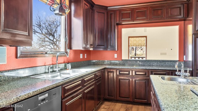 kitchen featuring light hardwood / wood-style flooring, dark stone countertops, sink, and stainless steel dishwasher