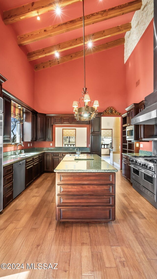 kitchen featuring hanging light fixtures, light hardwood / wood-style flooring, light stone counters, stainless steel appliances, and beam ceiling