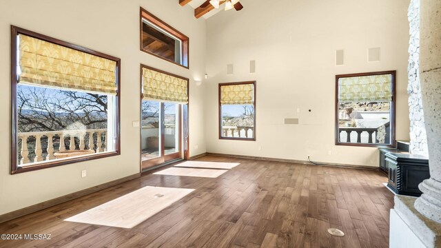 living room with ceiling fan, a towering ceiling, and hardwood / wood-style floors