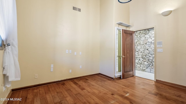 foyer entrance with baseboards, wood finished floors, and visible vents