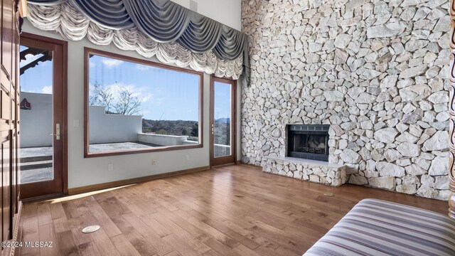 unfurnished living room featuring wood finished floors, a fireplace with raised hearth, and baseboards