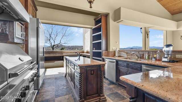 kitchen with vaulted ceiling, light stone countertops, stainless steel dishwasher, a center island, and sink