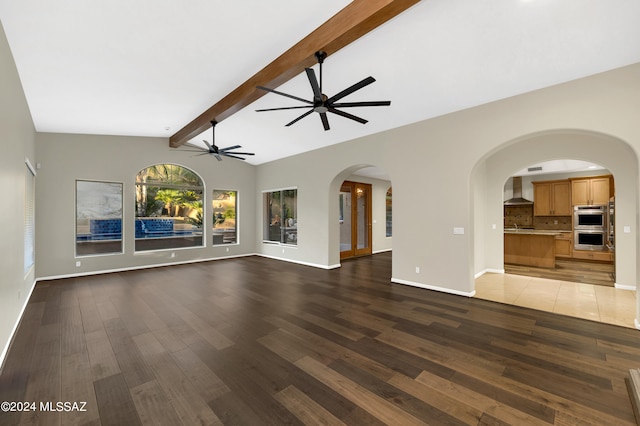 unfurnished living room with vaulted ceiling with beams, ceiling fan, and dark hardwood / wood-style flooring