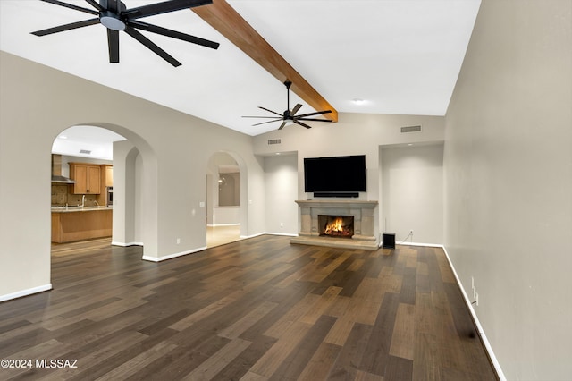 unfurnished living room with ceiling fan, beamed ceiling, dark wood-type flooring, and high vaulted ceiling