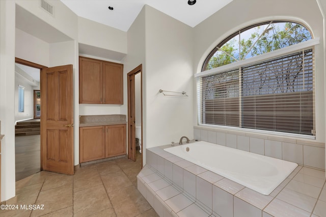 bathroom with tile patterned floors, tiled tub, and vanity