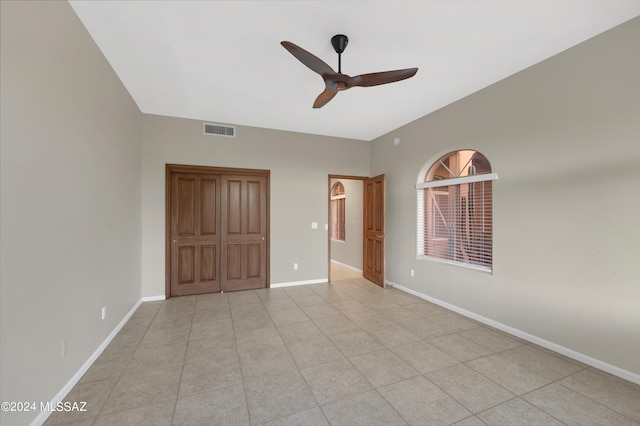 unfurnished bedroom with light tile patterned flooring, ceiling fan, and a closet