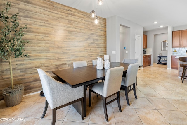 dining area with wood walls and light tile patterned floors