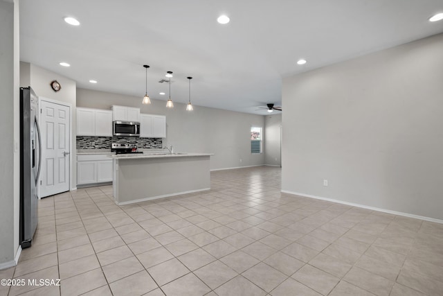 kitchen with decorative light fixtures, white cabinetry, ceiling fan, a center island with sink, and appliances with stainless steel finishes