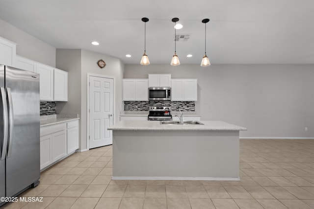 kitchen with appliances with stainless steel finishes, an island with sink, decorative light fixtures, and white cabinetry