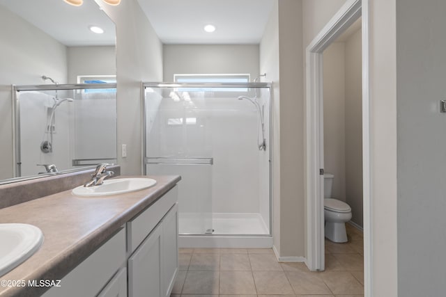 bathroom featuring toilet, a shower with door, tile patterned floors, and vanity