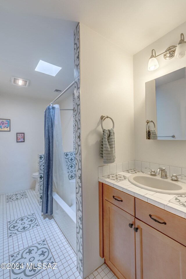 full bathroom featuring toilet, tile patterned flooring, vanity, a skylight, and shower / bath combo