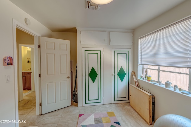 bedroom featuring ensuite bathroom and light tile patterned flooring