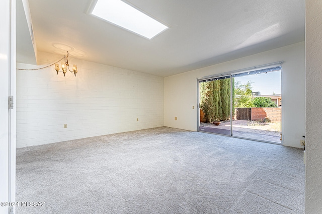 spare room with a textured ceiling, carpet, and a notable chandelier