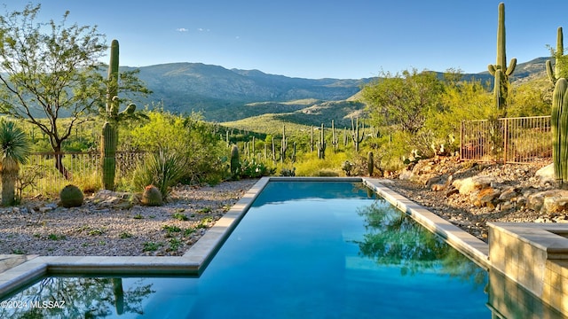 view of swimming pool featuring a mountain view and fence