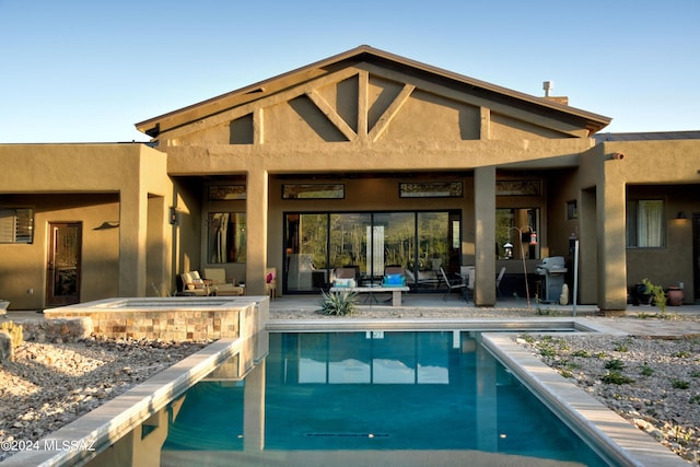 back of house with a patio, a pool with connected hot tub, and stucco siding