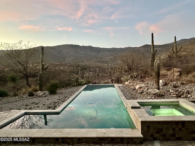 entry to storm shelter featuring a jacuzzi, fence, and a mountain view