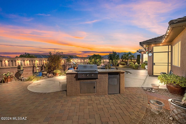 patio terrace at dusk with exterior kitchen and grilling area