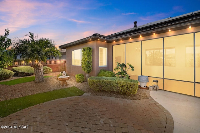 property exterior at dusk featuring a patio area