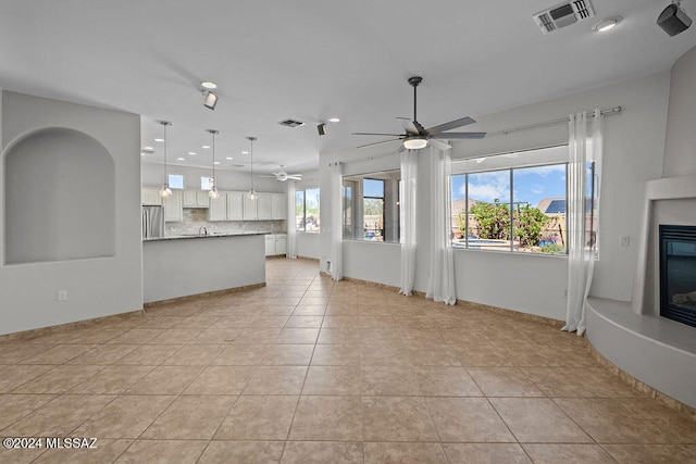 unfurnished living room featuring light tile patterned flooring, plenty of natural light, and ceiling fan