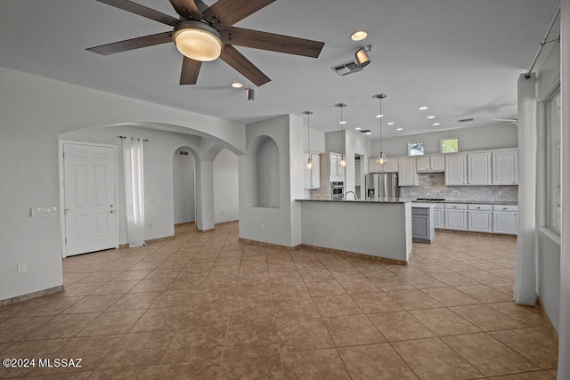 kitchen with light tile patterned floors, kitchen peninsula, backsplash, stainless steel fridge with ice dispenser, and white cabinetry