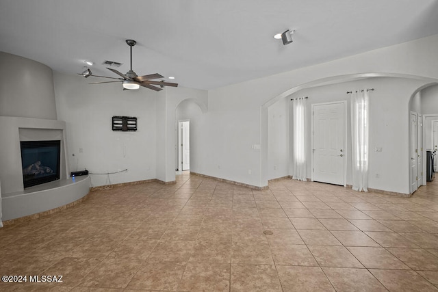 unfurnished living room with light tile patterned flooring, a fireplace, and ceiling fan