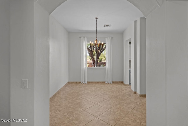 unfurnished dining area featuring an inviting chandelier and light tile patterned floors