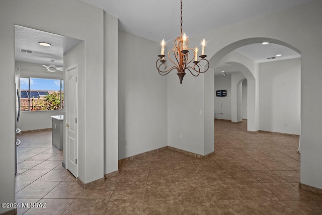 unfurnished dining area featuring ceiling fan with notable chandelier and light tile patterned floors