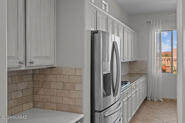 kitchen featuring light tile patterned flooring, stainless steel fridge, and white cabinetry