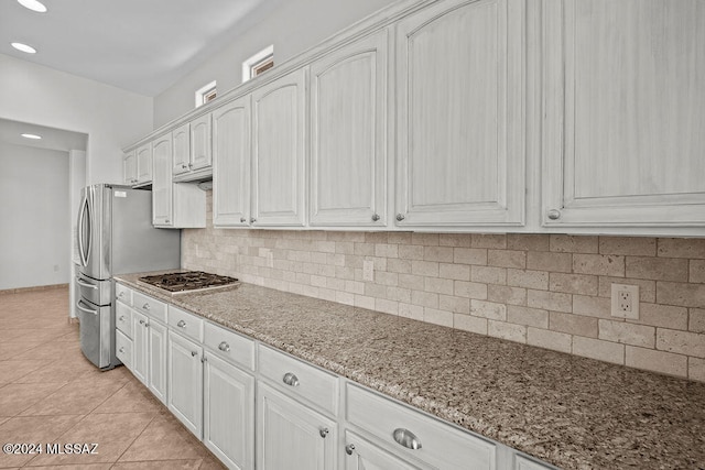 kitchen featuring light stone counters, tasteful backsplash, white cabinets, appliances with stainless steel finishes, and light tile patterned floors