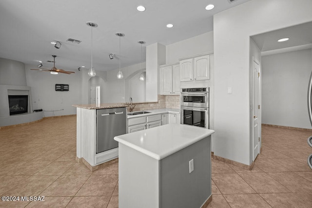 kitchen with stainless steel appliances, white cabinets, light tile patterned flooring, kitchen peninsula, and decorative light fixtures