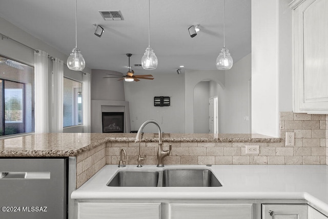 kitchen with ceiling fan, white cabinets, sink, a large fireplace, and dishwasher