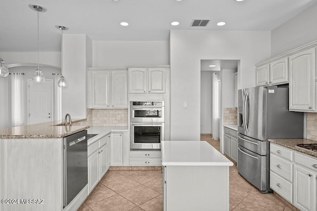 kitchen featuring white cabinets, kitchen peninsula, appliances with stainless steel finishes, decorative light fixtures, and light tile patterned floors