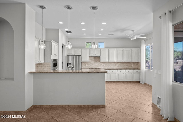 kitchen with appliances with stainless steel finishes, kitchen peninsula, light stone counters, and white cabinets