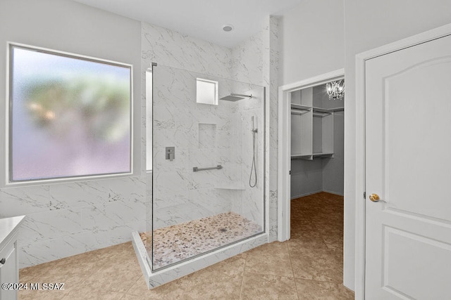 bathroom featuring a tile shower, tile patterned floors, an inviting chandelier, and vanity